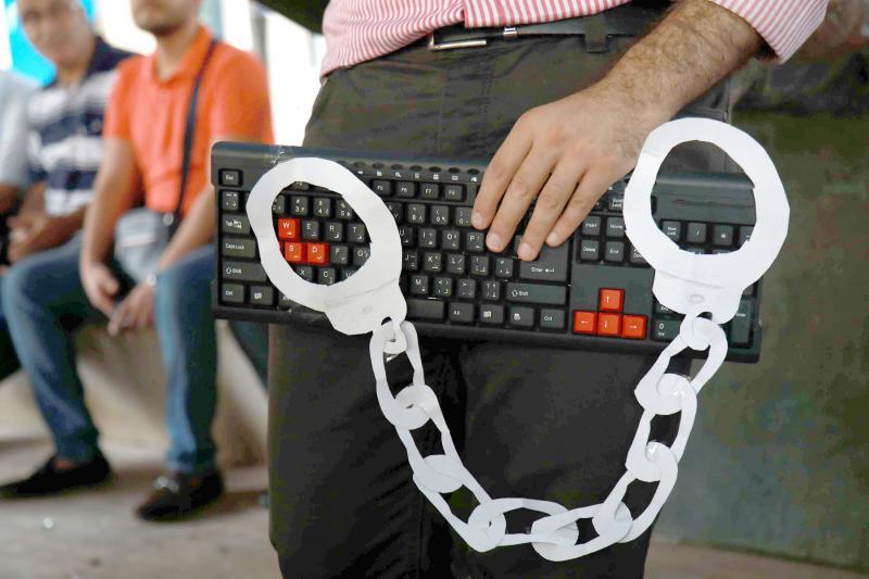 An activist holds a computer keyboard and makeshift handcuffs in Beirut? on July 24
