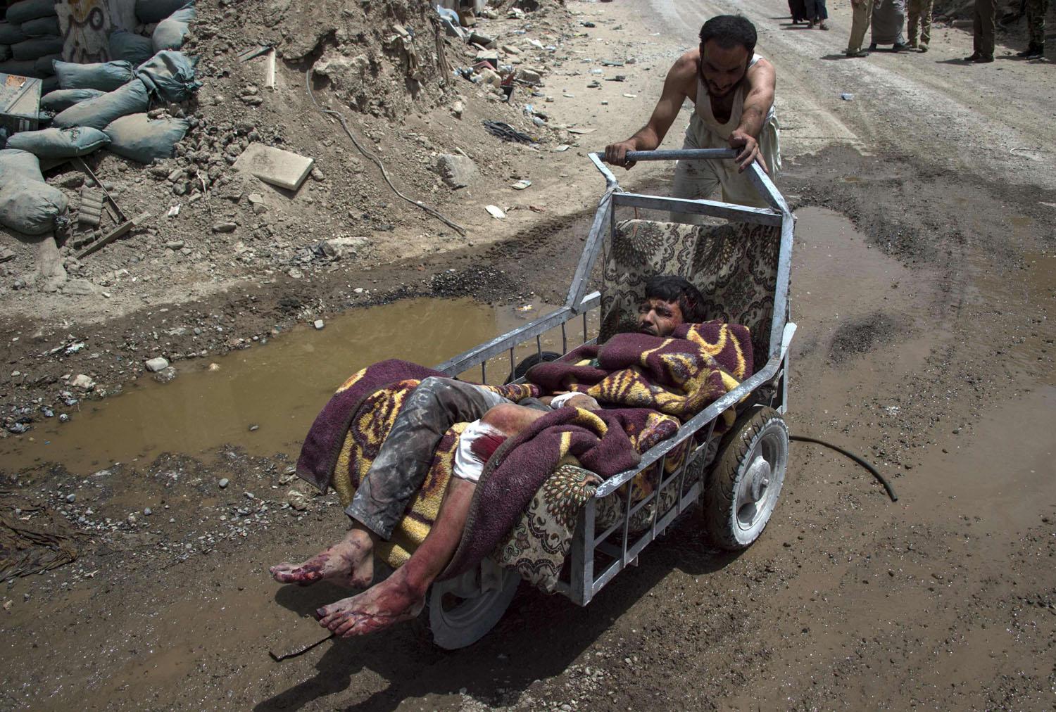 عراقي يدفع عربة فيها جريح في الموصل