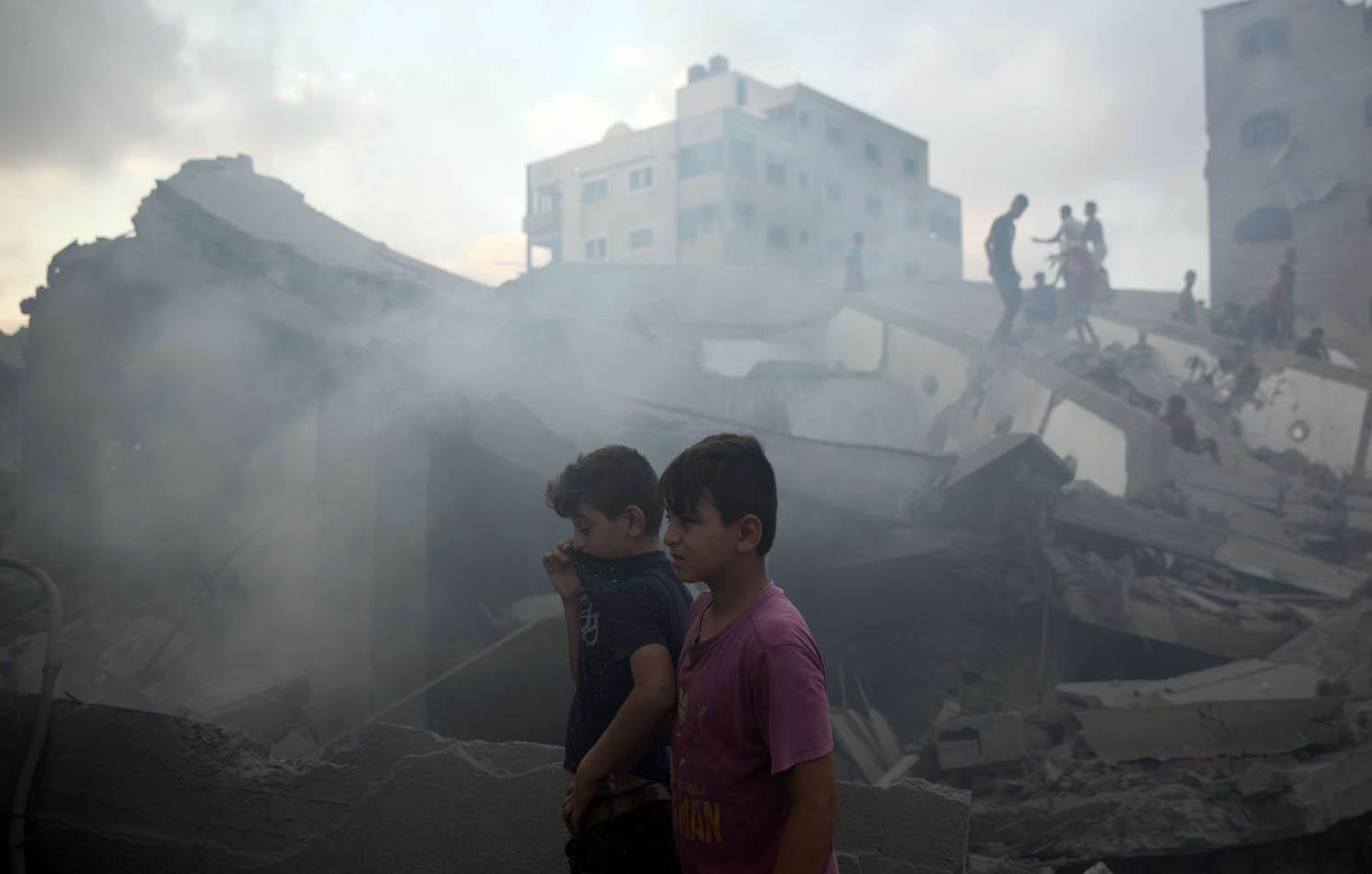 أطفال فلسطينيون بالقرب من مبنى دمرته الغارات الاسرائيلية في غزة