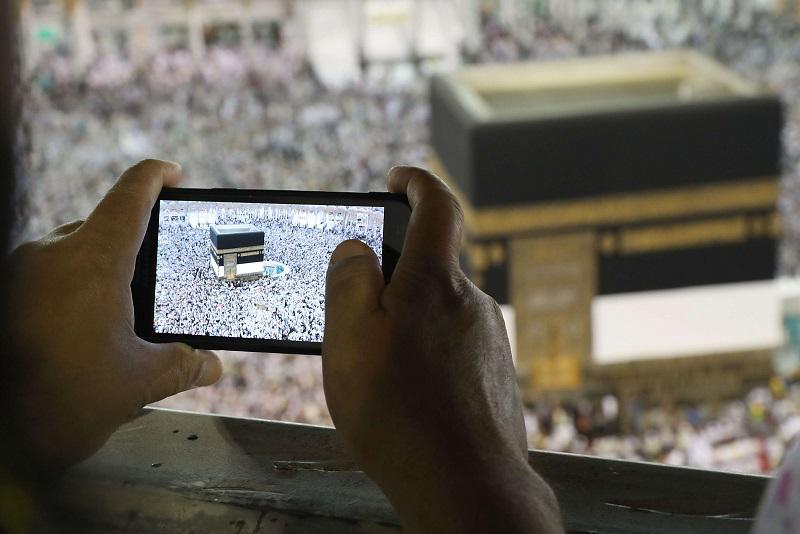 يد تمسك هاتفا ذكيا لتصوير الكعبة