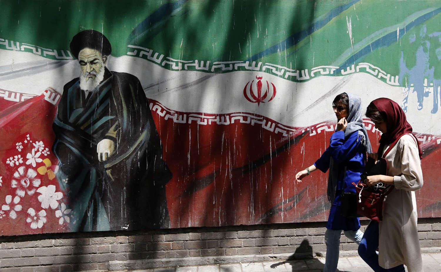 إيرانيات بالقرب من لوحة جدارية للخميني
