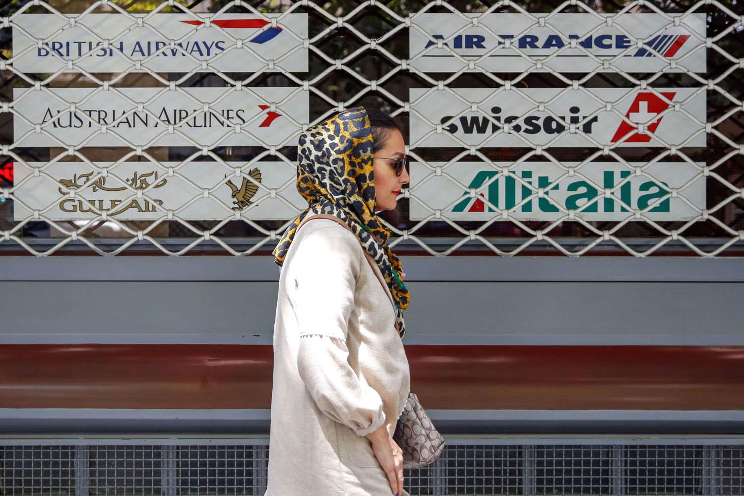  إيرانية تمر من أمام وكالة اسفار مغلقة بعد ايقاف شركات عالمية رحلاتها إلى طهران