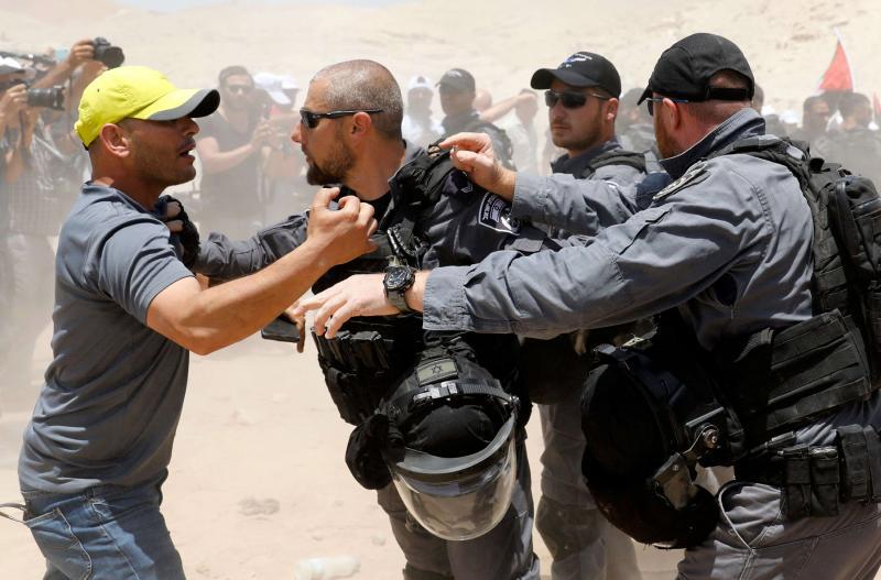 A demonstrator scuffles with Israeli policemen in the Palestinian Bedouin village of Khan al-Ahmar