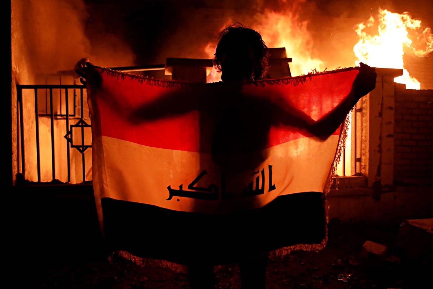 عراقي يرفع علما أمام مبنى البلدية المحترق في البصرة