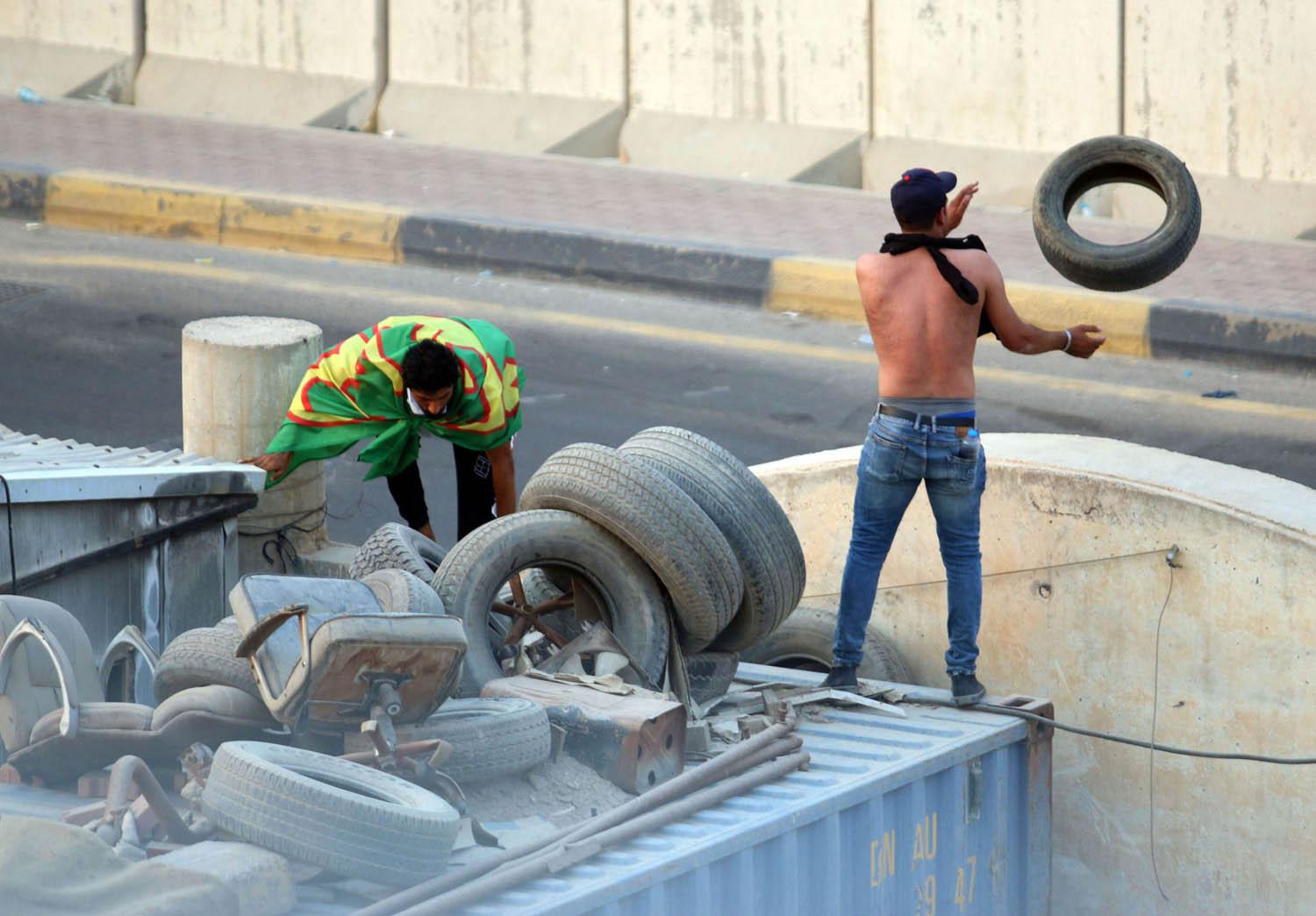 عراقي يلقي بإطارات وسط شارع في مدينة البصرة استعدادا لحرقها