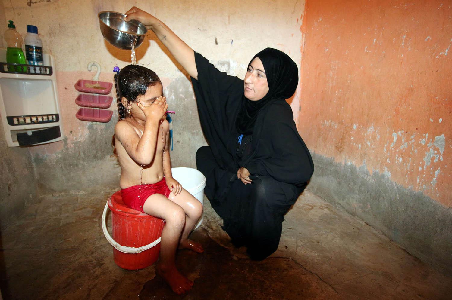 عراقية تصب الماء على طفلتها لتستحم في مدينة التنومة في البصرة