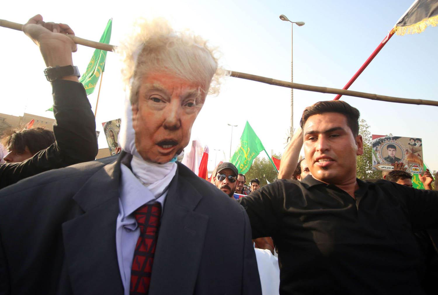 متظاهر يلوح بدمية على شكل الرئيس الأميركي ترامب