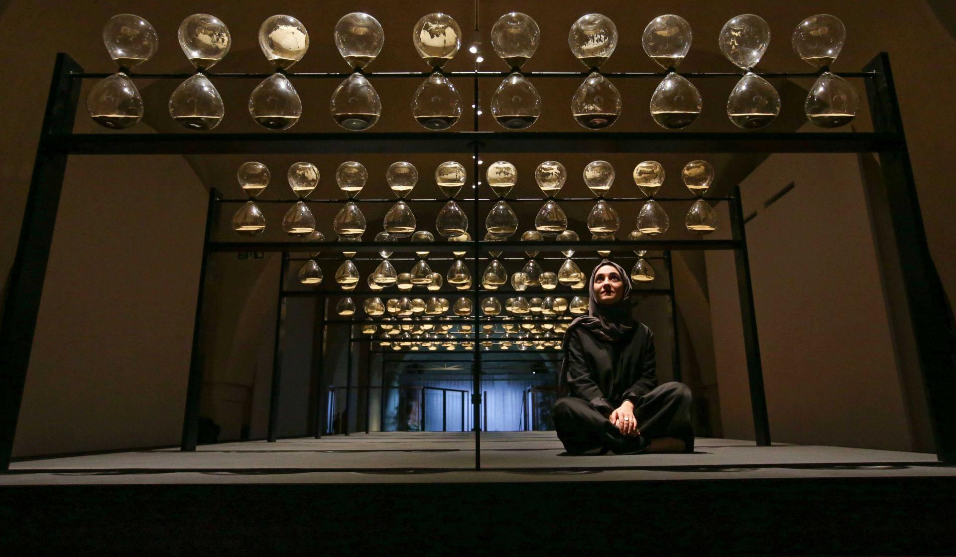 Co-designer Kholoud Sharafi poses inside the artwork entitled 'United Arab Emirates, Time is Subjective' by designers Reem Al Ghaith, Kholoud Sharafi, Carlos Gris, Hamza Al Omari, and Claudia Rivera