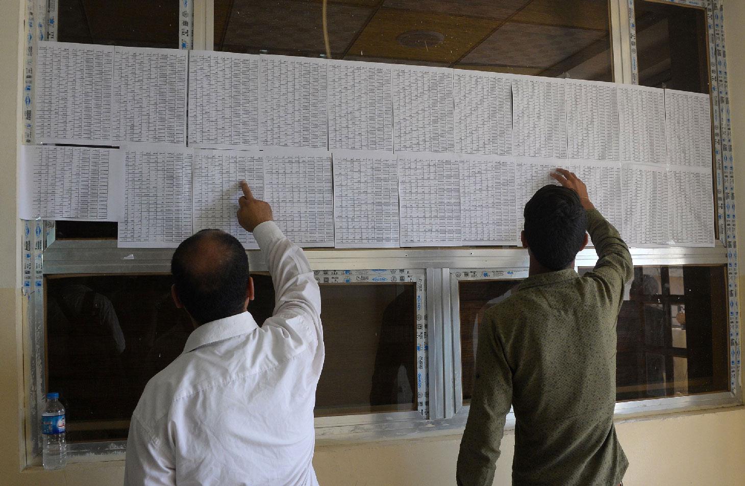 Iraqis check lists of names at the Nineveh governorate building in Mosul.
