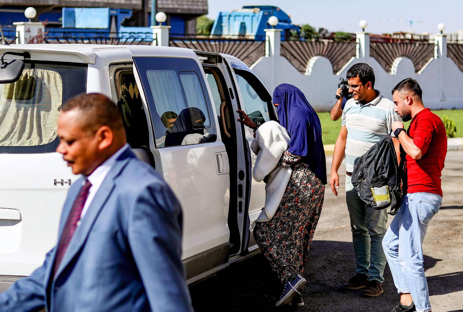 Sudanese woman (C) carrying a one-month-old baby being escorted into a vehicle in Syria's northeastern city of Qamishli.