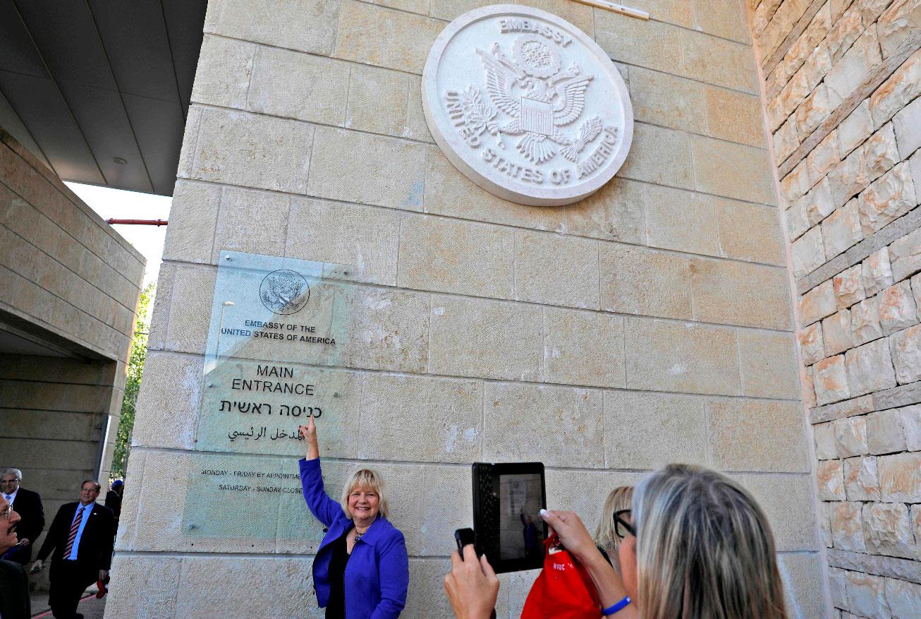 A woman poses for a picture next to an inauguration plaque during the opening of the US embassy in occupied Jerusalem.
