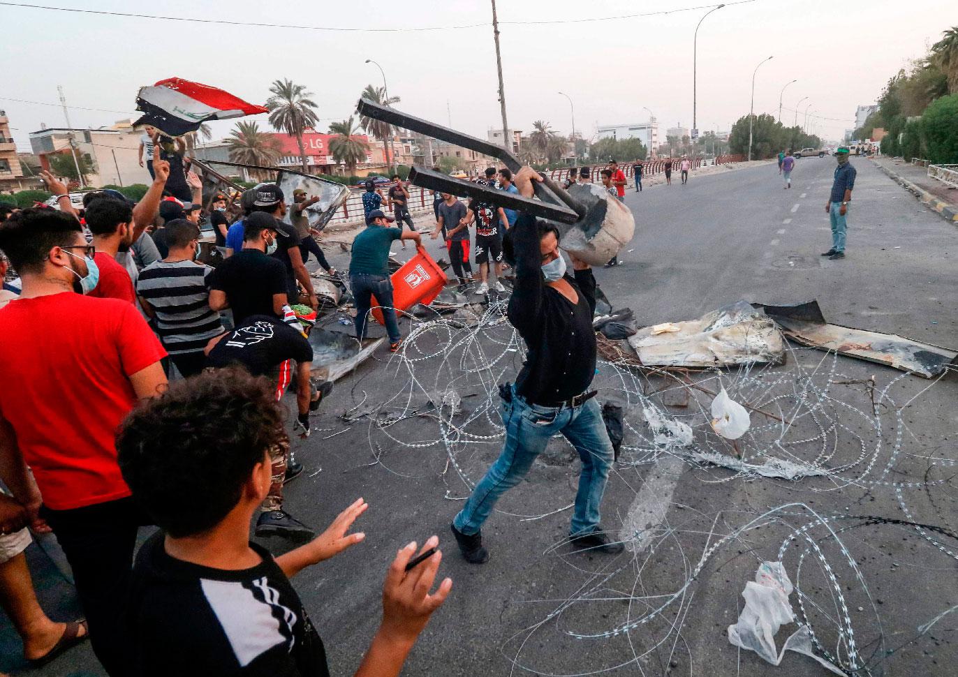 In this file photo taken on September 2, 2018, Iraqi protesters gather trash cans and scrap with barbed wire as they erect a make-shift barricade during clashes with security forces following a demonstration against corruption and lack of basic services outside the local government headquarters in the southern city of Basra.