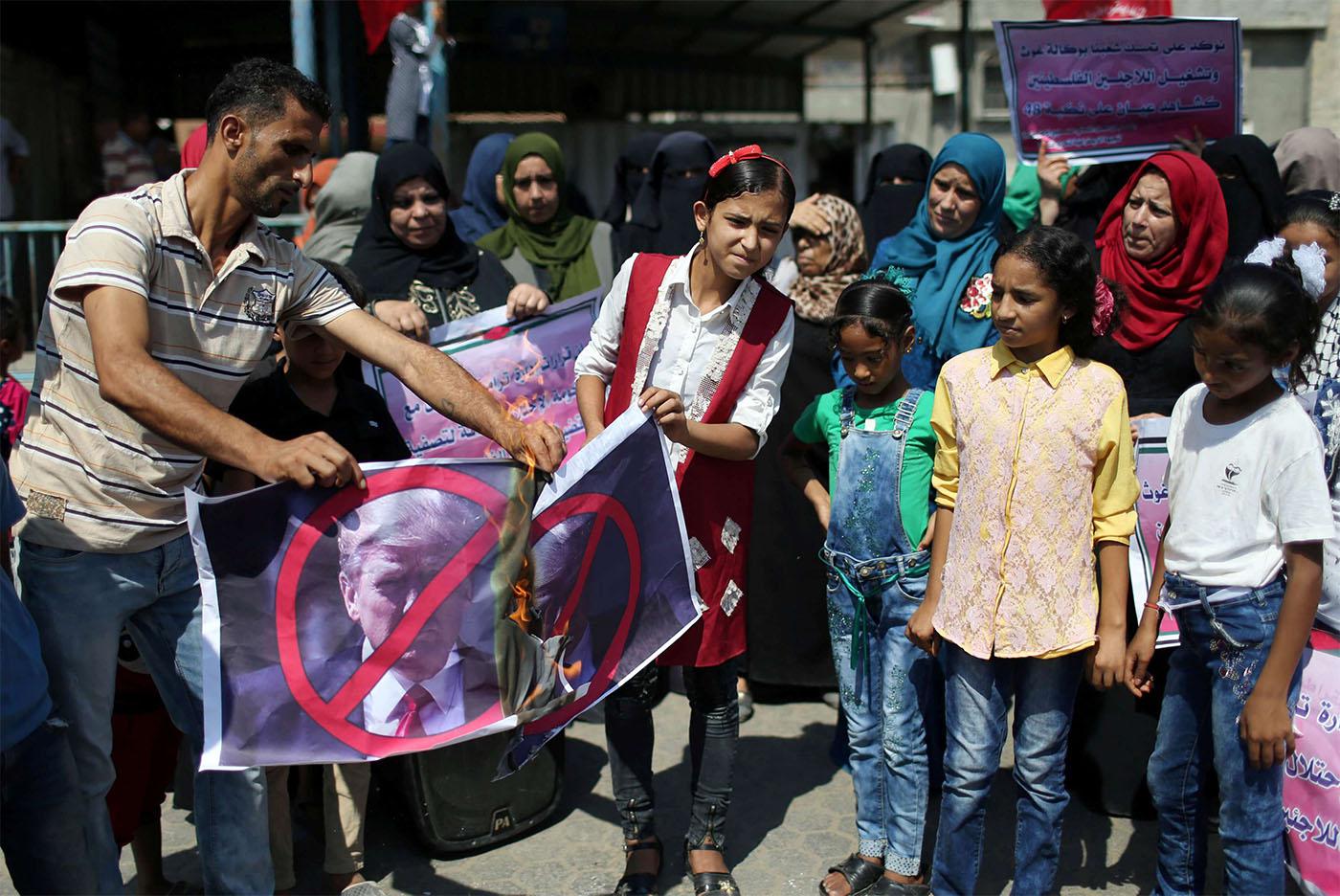 Palestinians burn Donald Trump's picture during a protest against a US decision to cut funding to UNRWA