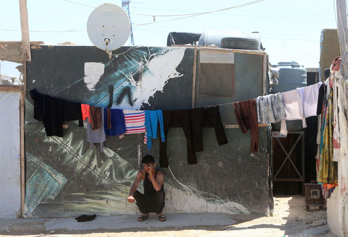 A young Syrian man sits outside a tent in a refugee camp on the outskirts of the town of Zahle in Lebanon's Bekaa Valley on June 23, 2018.