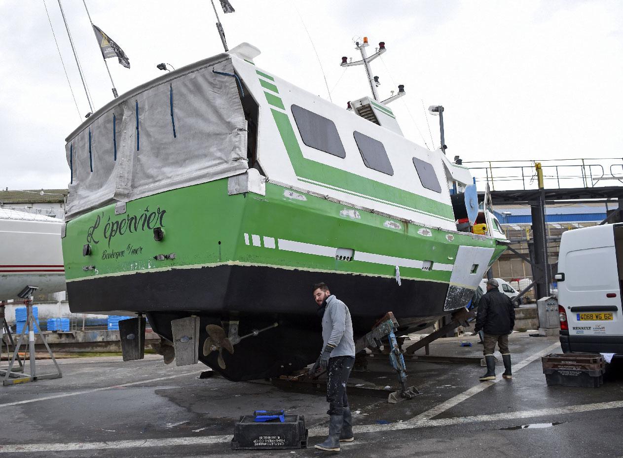 French workers repair "L'Epervier" on November 29, 2018, a boat that was stolen and damaged by migrants who tried to cross the English Channel, in Wissant, northern France.