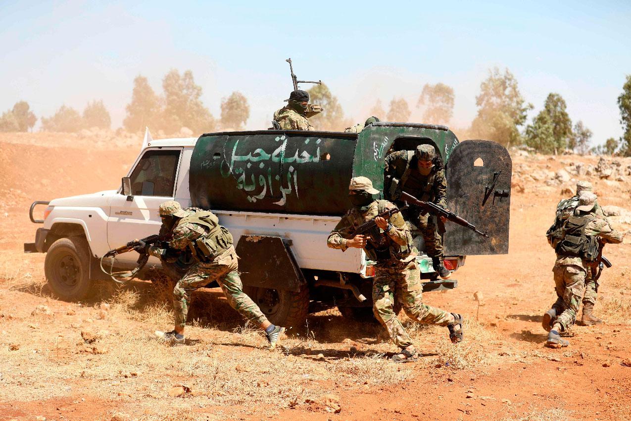 In this file photo taken on August 14, 2018 Syrian fighters attend a mock battle in anticipation of an attack by the regime on Idlib province and the surrounding countryside, during a graduation of new Hayat Tahrir al-Sham (HTS) members at a camp in the countryside of the northern Idlib province.