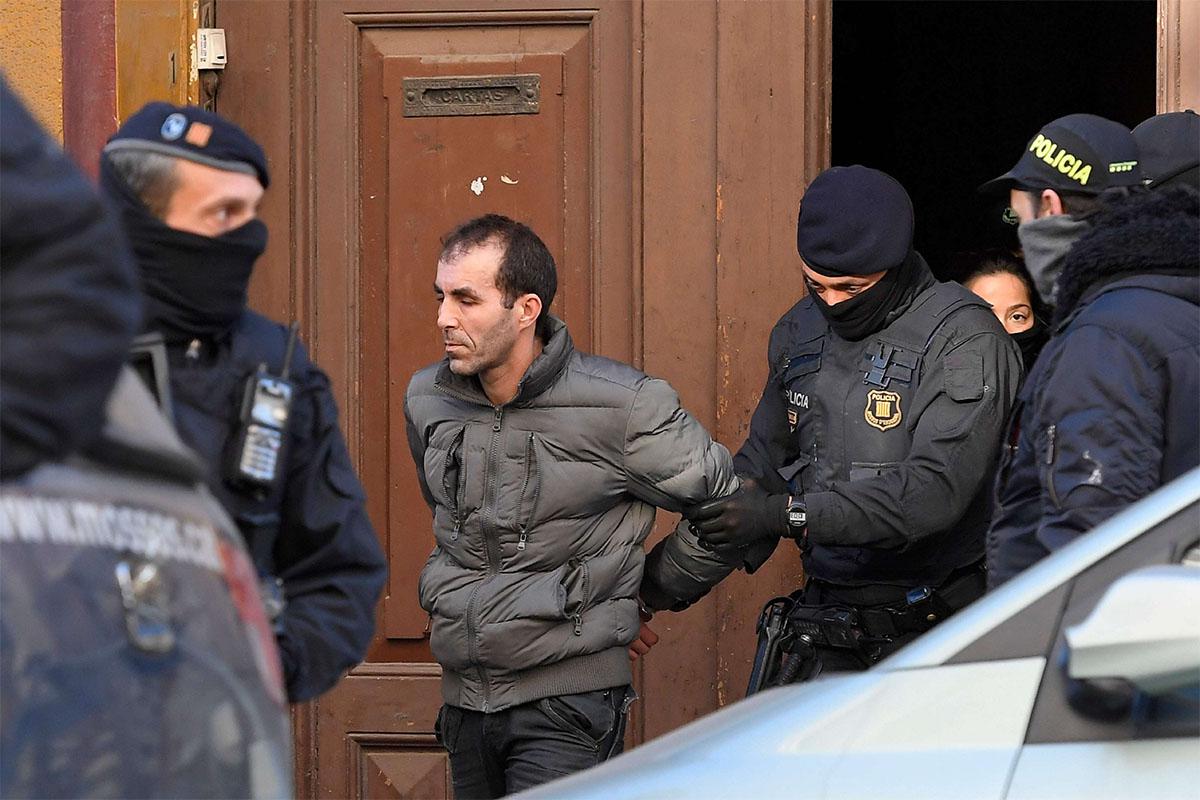 A man is escorted by Catalan regional police officers 'Mossos D'Esquadra" during a counter-terrorism operation