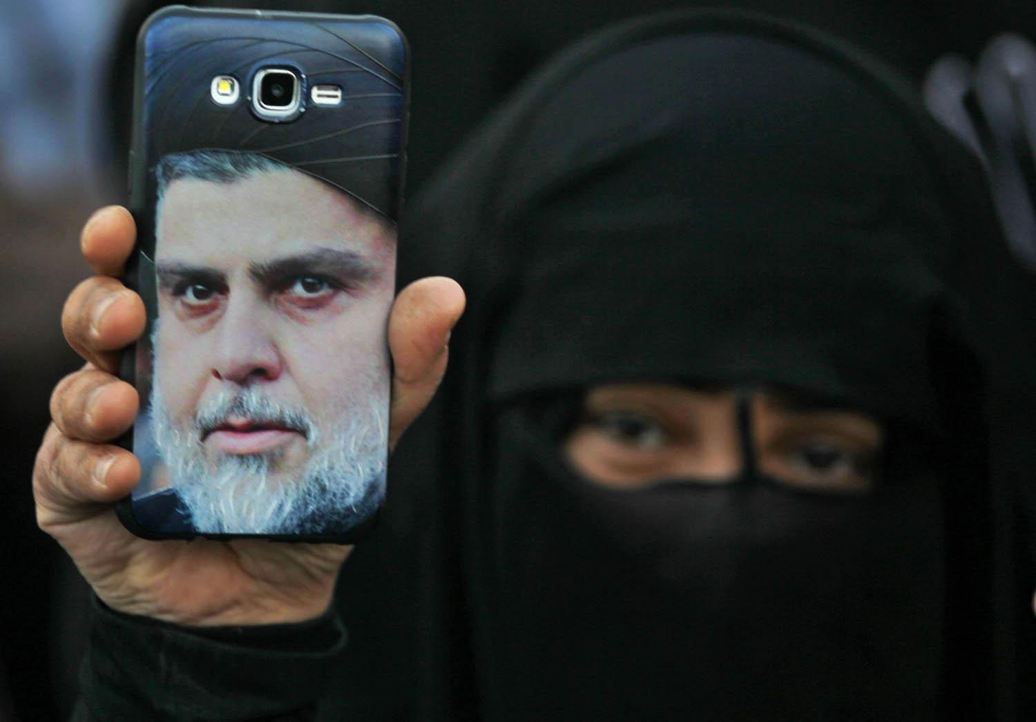 عراقية ترفع صورة مقتدى الصدر في تظاهرة احتجاج على الحكومة وسط بغداد
