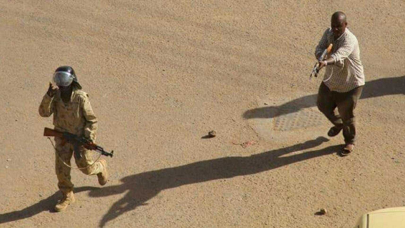 In this Dec. 25, 2018 file image, provided by a Sudanese activist, a plain clothed policeman points his rifle at protesters during clashes in Khartoum, Sudan.