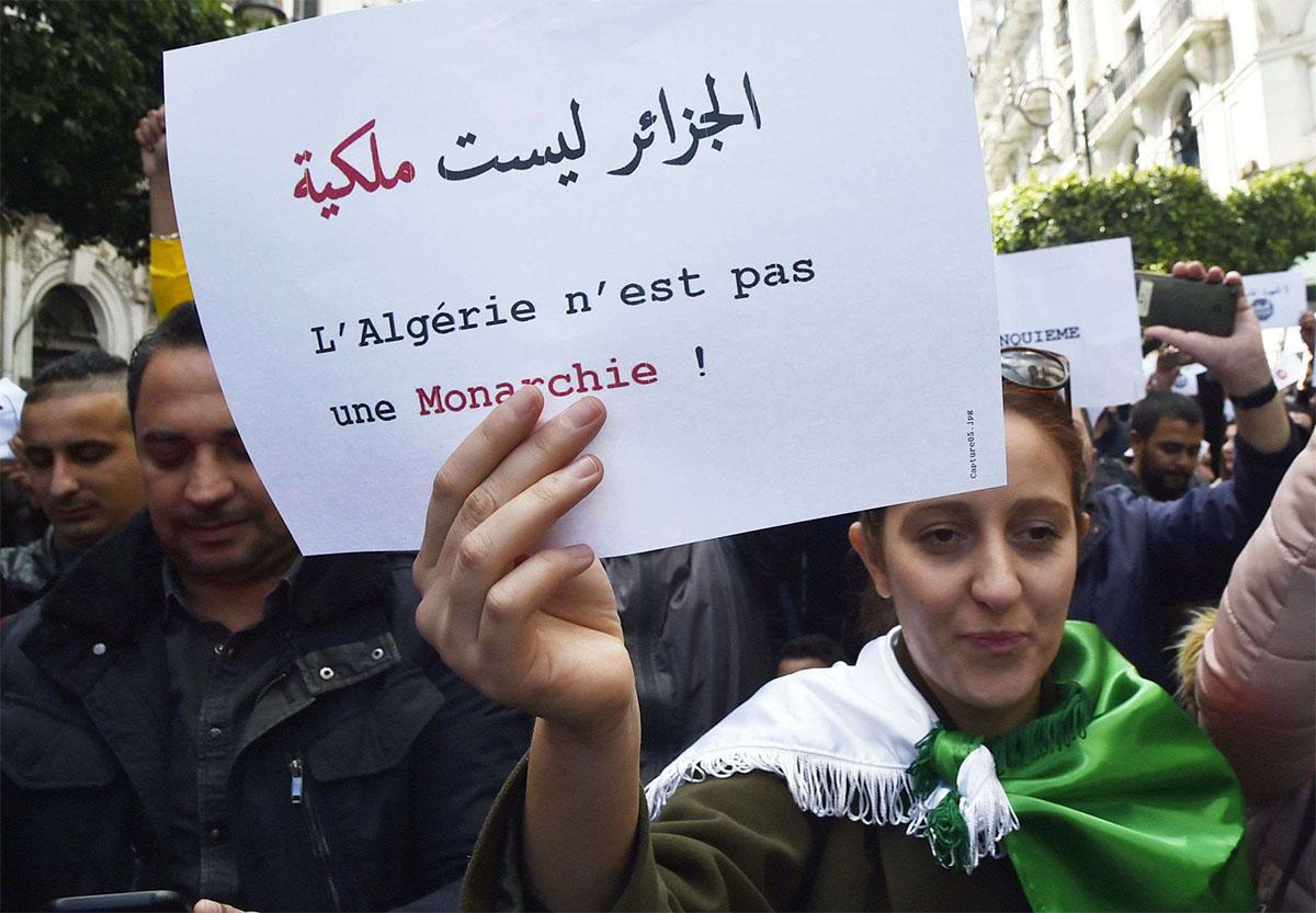 An Algerian protester holds a sign which reads in Arabic and French: "Algeria is not a monarchy" 