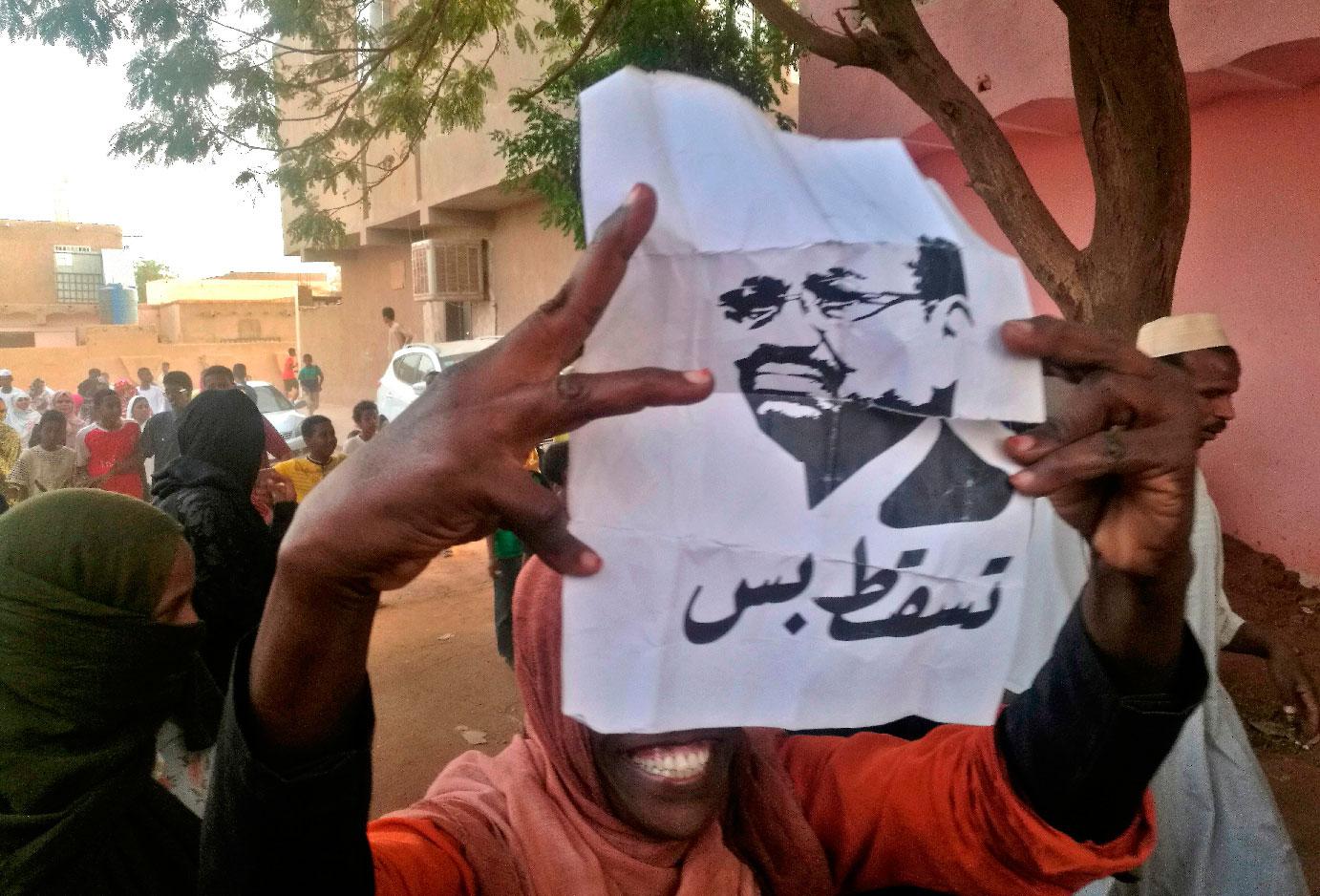A Sudanese protester carries a portrait of President Omar al-Bashir with Arabic writing that reads "down and that is all" during an anti-government demonstration east of the capital Khartoum on February 9, 2019.