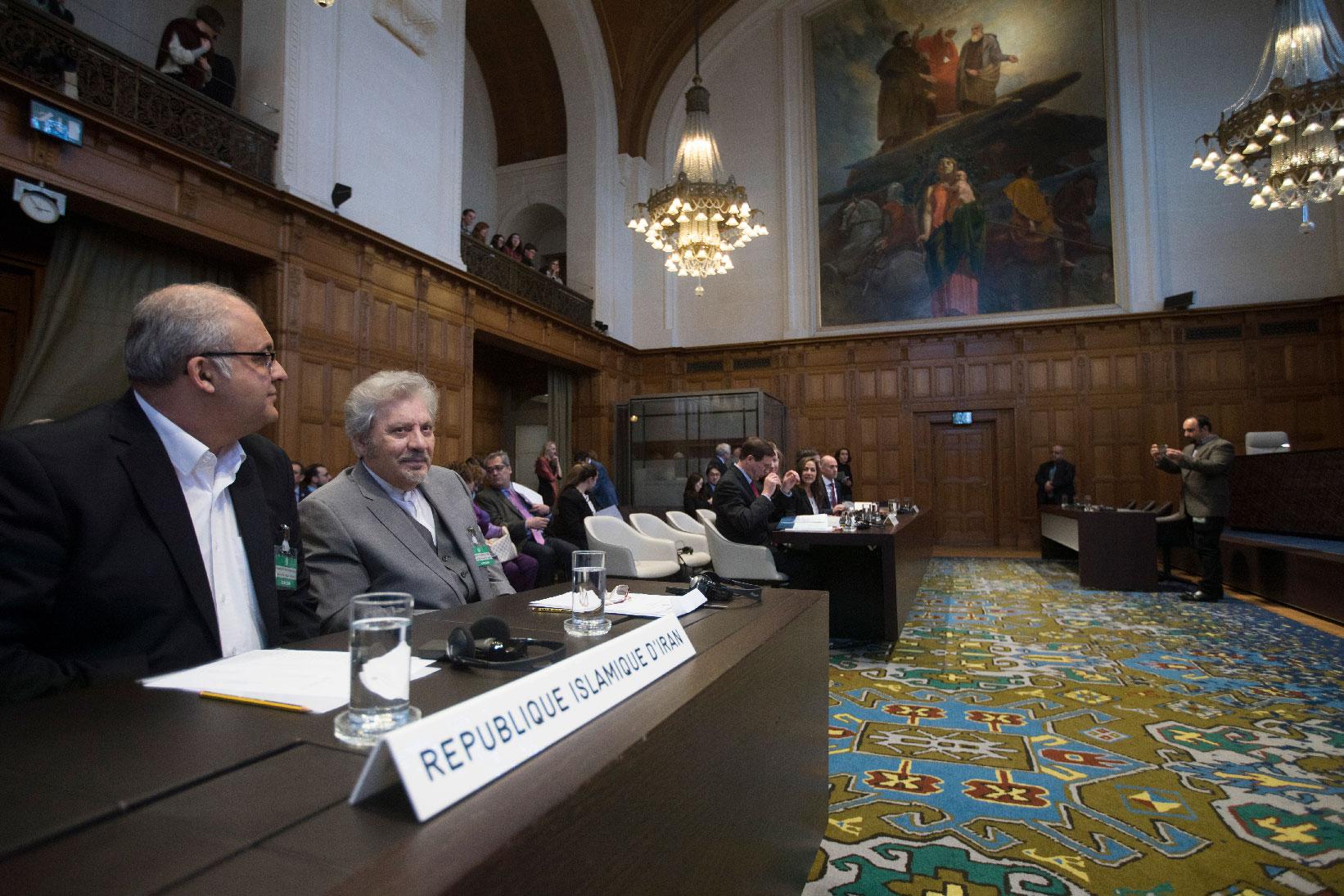 Mohsen Mohebi, agent for the Islamic Republic of Iran, second left, and his delegation take their seats, as the U.S. delegation is seen in the background, right, as they wait for judges to enter the International Court of Justice, or World Court, in The Hague, Netherlands, Wednesday, Feb. 13, 2019.