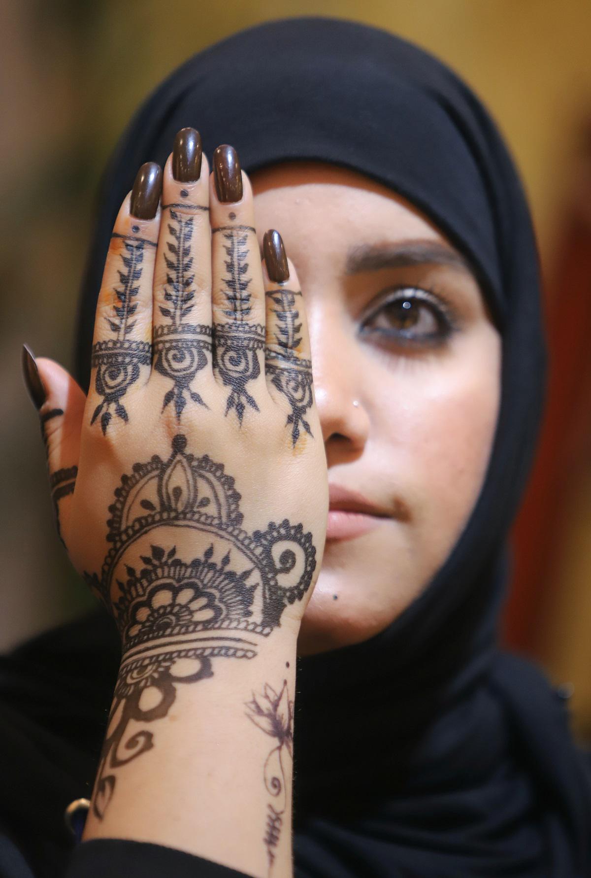 فتاة عراقية تخضب كفها بالحناء في صالون تجميل في البصرة