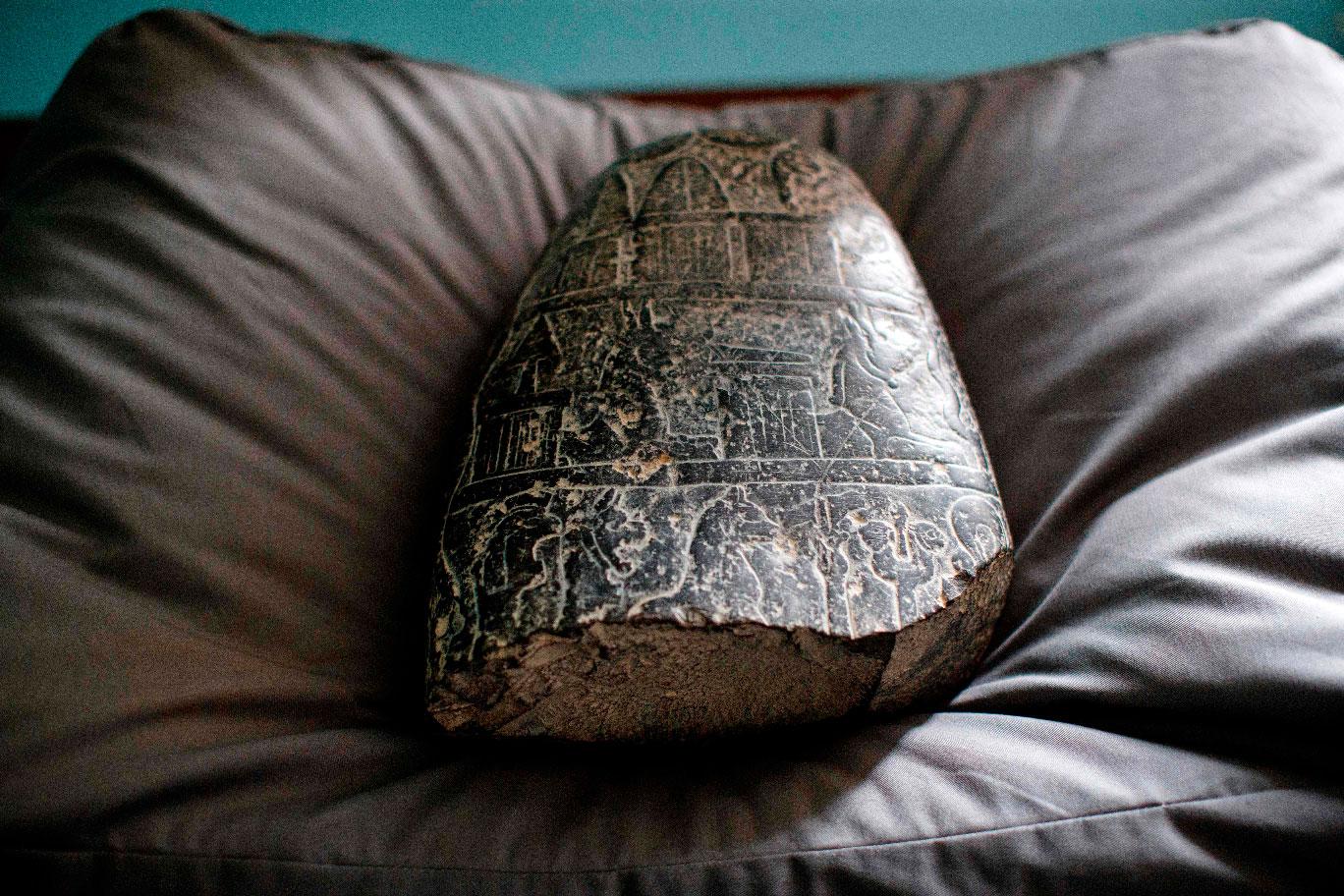 A Babylonian cuneiform kudurru (boundary stone) which was looted from Iraq sits on a cushion at the British museum in London on March 19, 2019.