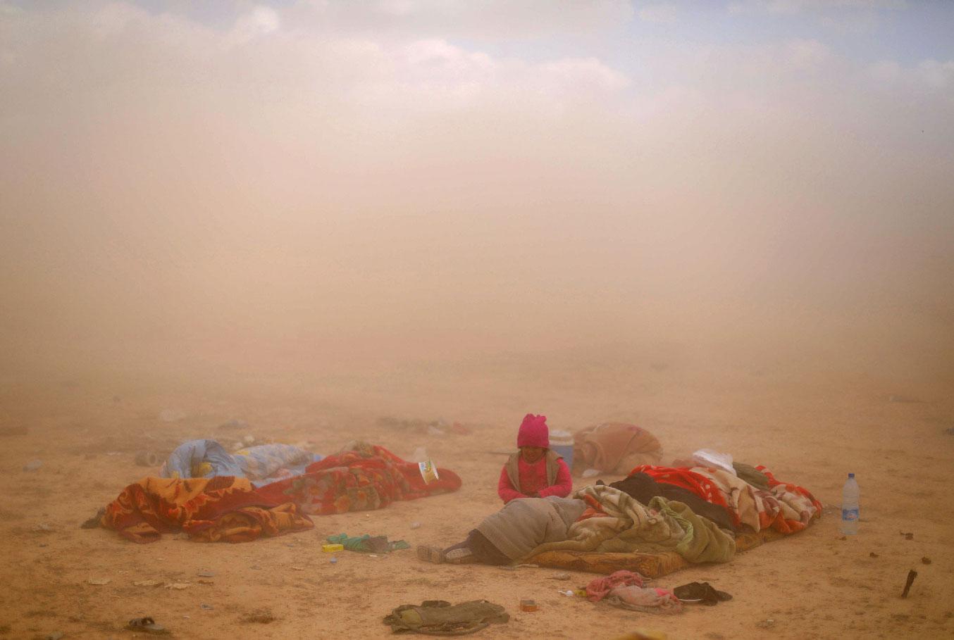 Children sit next to their injured mother near the village of Baghouz, Deir Ezzor province, in Syria March 7, 2019.