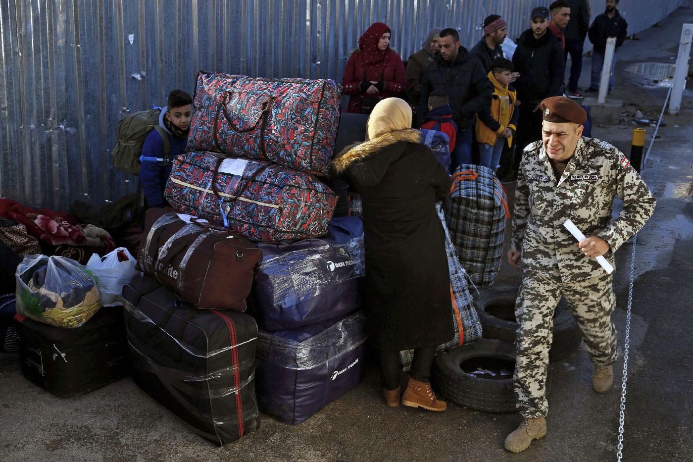 A member of the General Security Directorate, in charge of foreigners in Lebanon, passes by Syrian refugees waiting to board buses to take them home to Syria, in the northern Beirut suburb of Burj Hammoud, Lebanon, Thursday, Jan. 24, 2019.