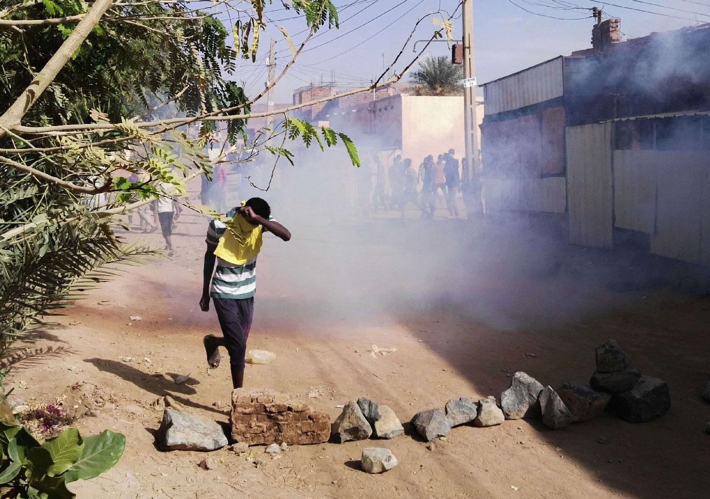 A Sudanese protester covers his face from tear gas during an anti-government demonstration in the Sudanese capital Khartoum's district of Burri on February 24, 2019.