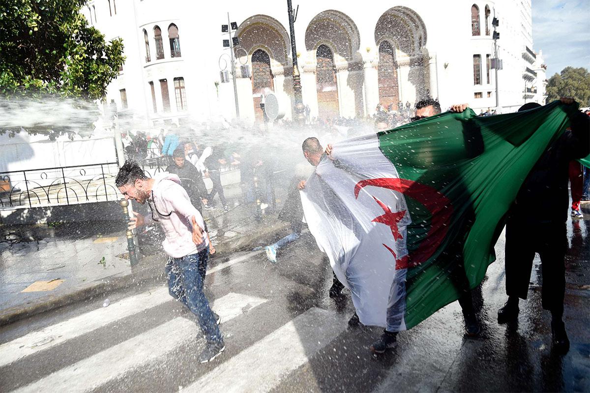 Riot police spray protesters with water during a protest in Algiers against Bensalah's appointment