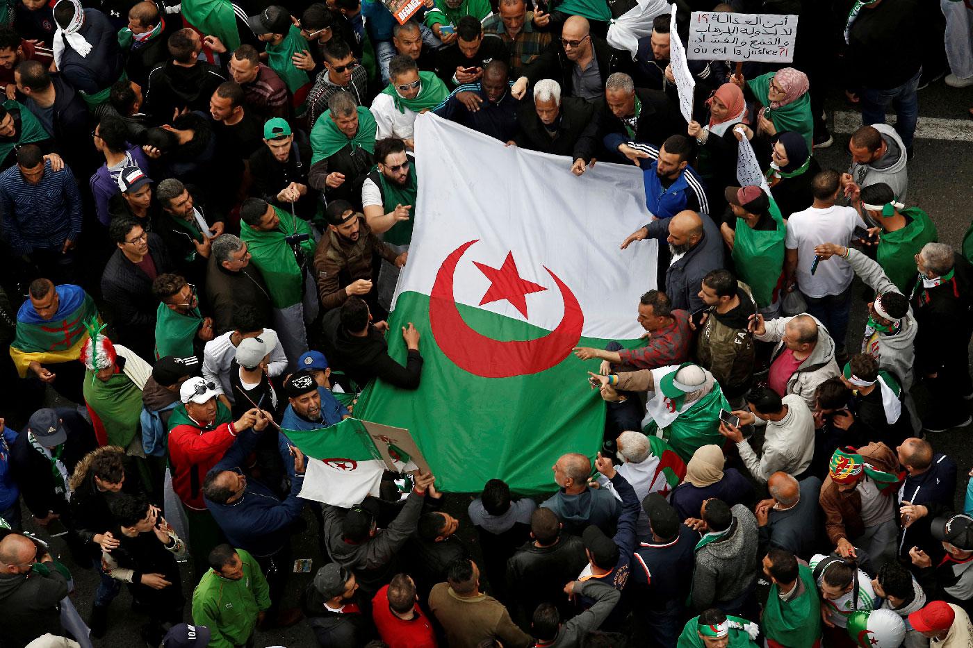 Demonstrators hold flags and banners as they return to the streets in Algiers