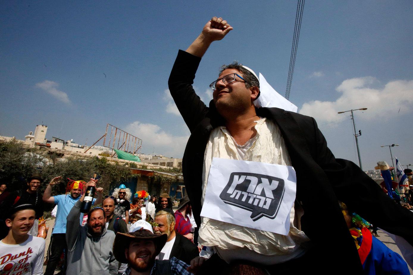 Jewish settlers carry Itamar Ben-Gvir, Jewish Power party leader, as they celebrate the Jewish Purim holiday at al-Shuhada street in the occupied Palestinian town of Hebron on March 21, 2019.