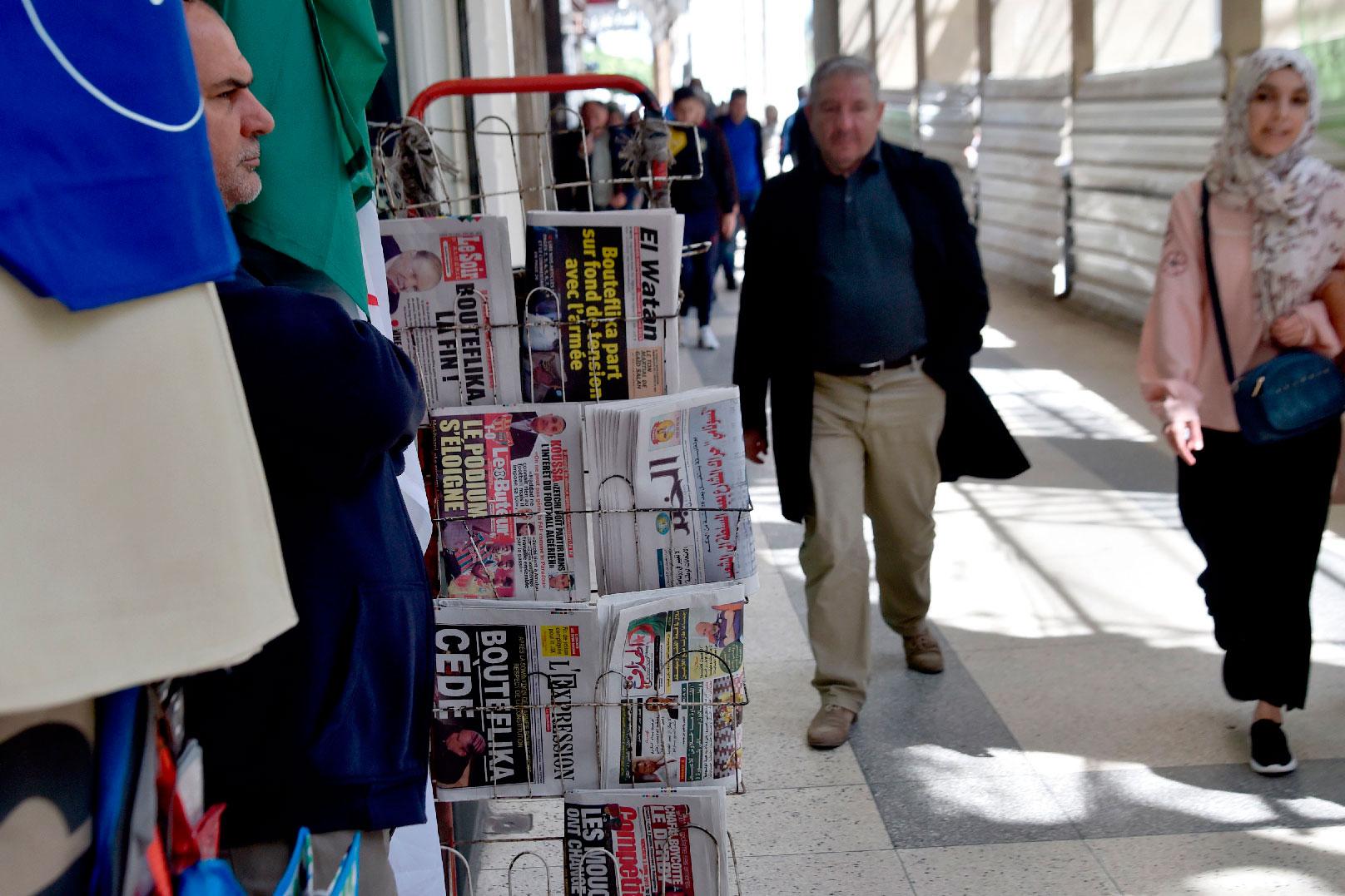 Algerians walk past newspapers reading "Bouteflika leaves" the day after Algeria's veteran President Abdelaziz Bouteflika informed the Constitutional Council that he was resigning, in Algiers on April 3, 2019.