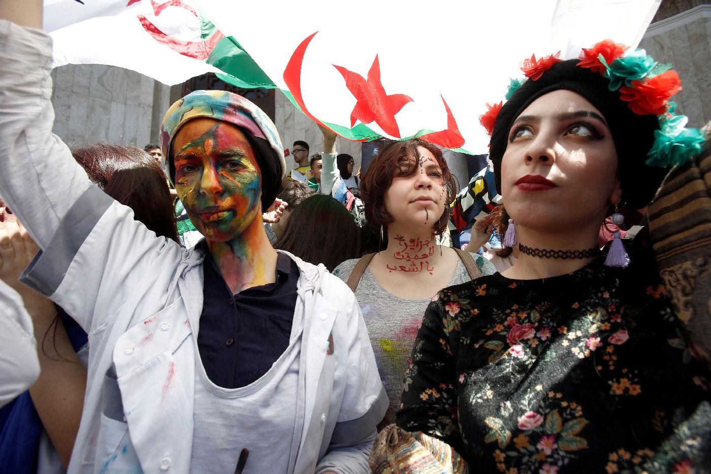 Demonstrators with painted faces hold flags during anti government protests in Algiers
