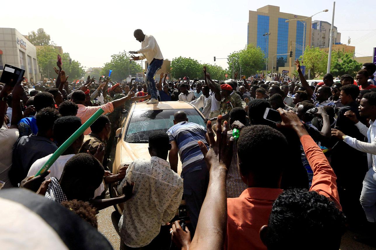 Sudanese demonstrators block the vehicle of a military officer in Khartoum