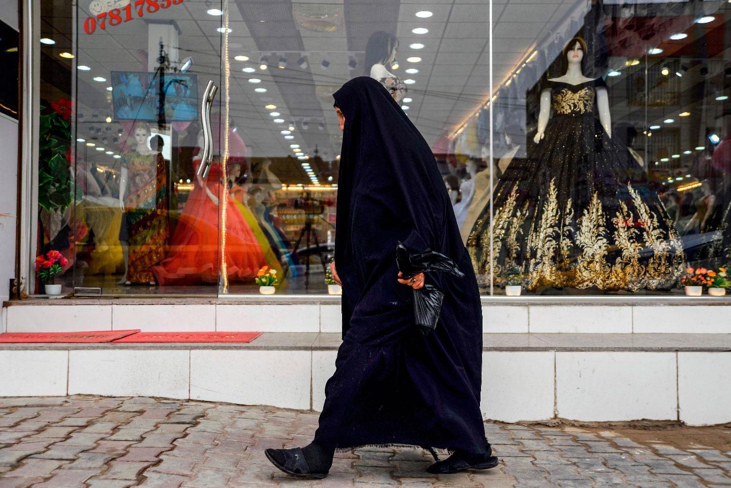 A woman walks past a dress shop in the central Iraqi city of Diwaniya on March 31, 2019