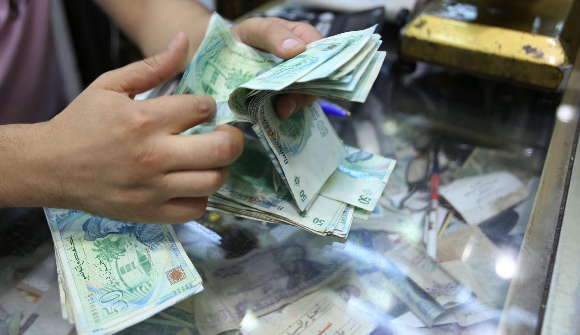 A shopkeeper counts money in his shop at a bazaar in Tunis