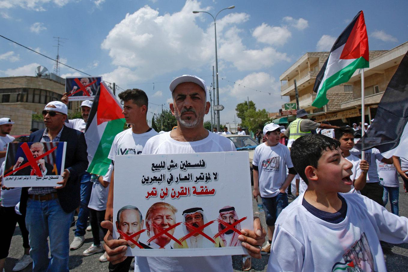 A man holds a protest sign with a caption in Arabic reading "Palestine is not for sale"