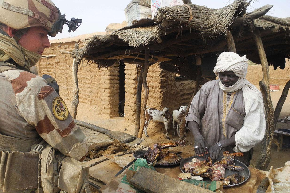 A French soldier speaks with a shopkeeper selling meat at his stall, in Gossi, central Mali
