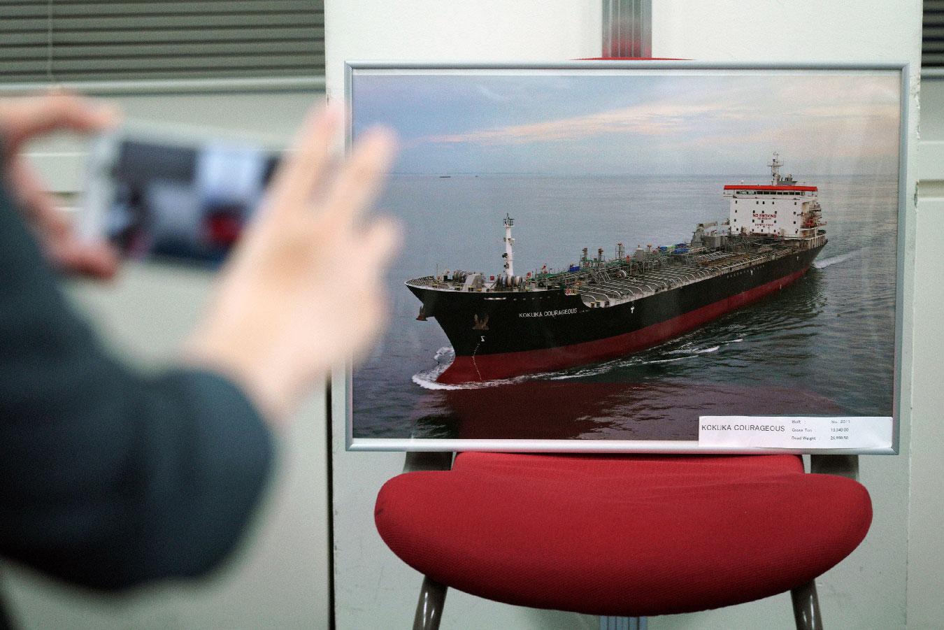 A journalist photographs a picture of the Kokuka Courageous, which was attacked near the Strait of Hormuz