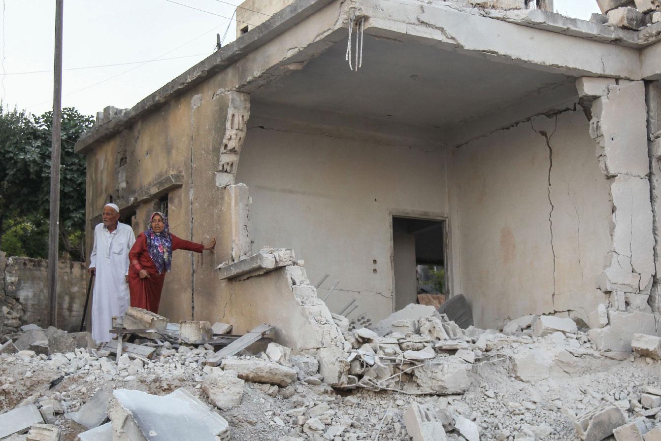 Syrians inspect the damage following reported regime airstrikes on the town of Muhambal