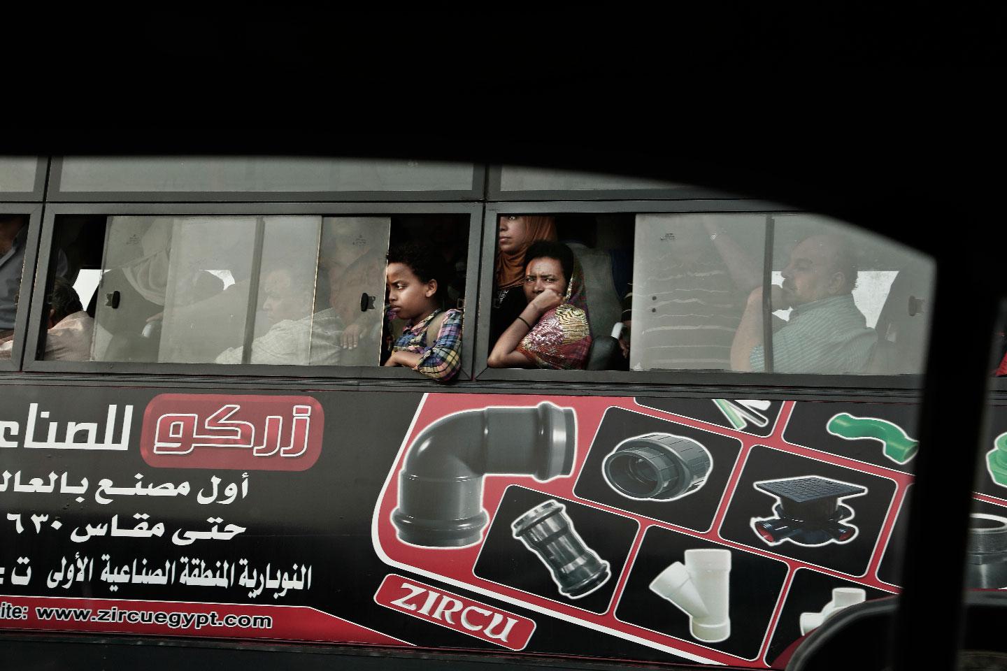 Commuters ride a public bus as they wait in traffic, in Cairo