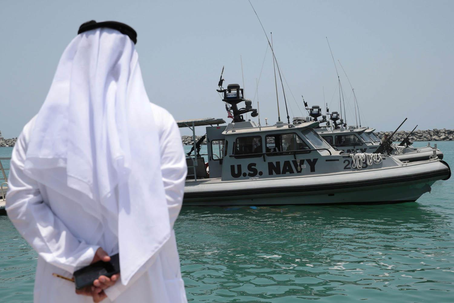 إماراتي ينظر إلى طرادات حربية أميركية في ميناء الفجيرة