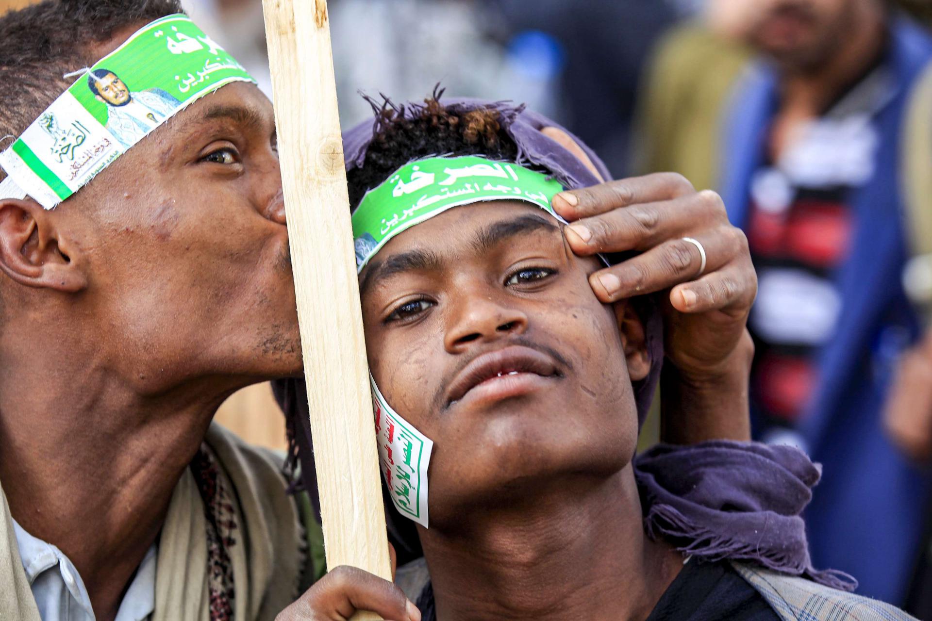 A supporter of Yemen's Huthi rebels kisses the forehead of another during a demonstration in the Huthi-held capital Sanaa