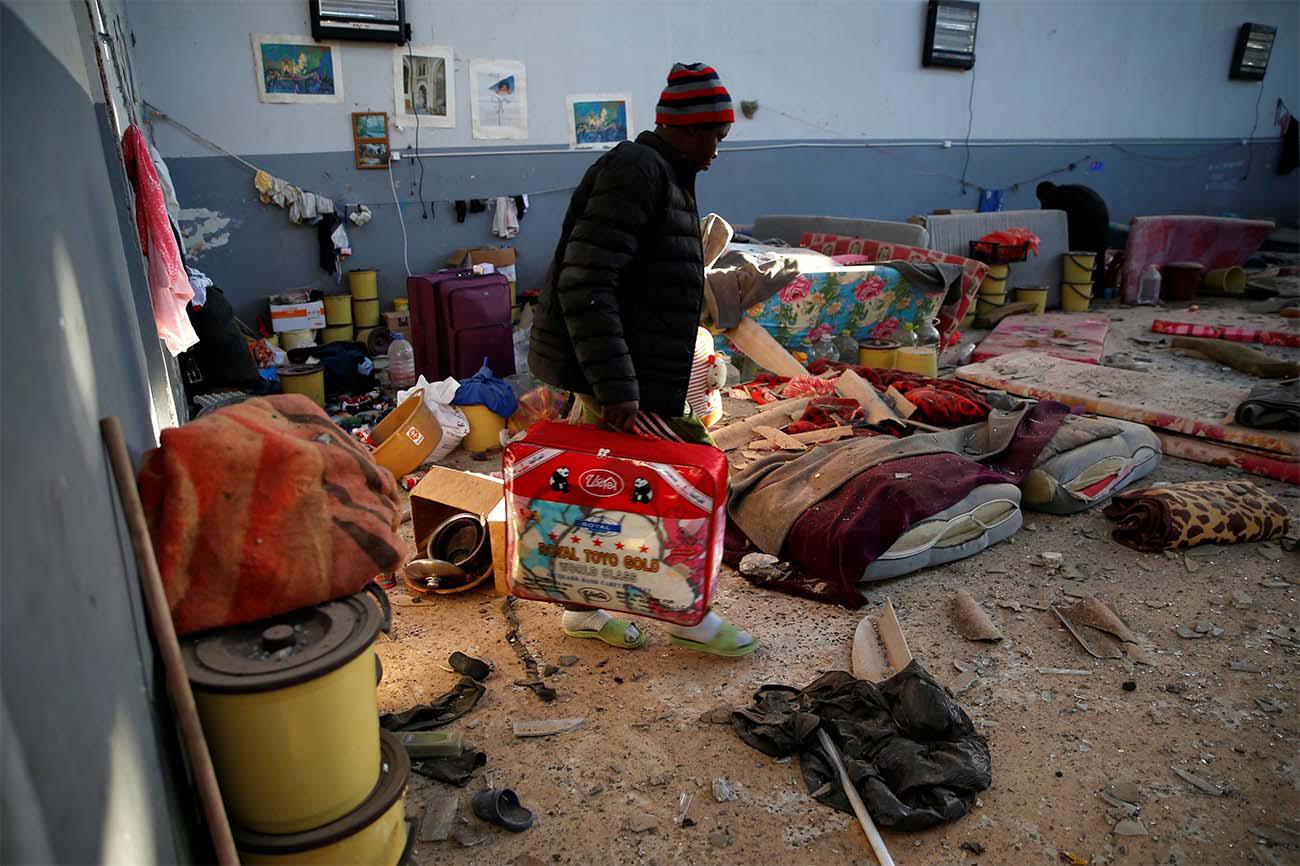 A migrant carries his belongings at a detention centre for mainly African migrants in Tajoura