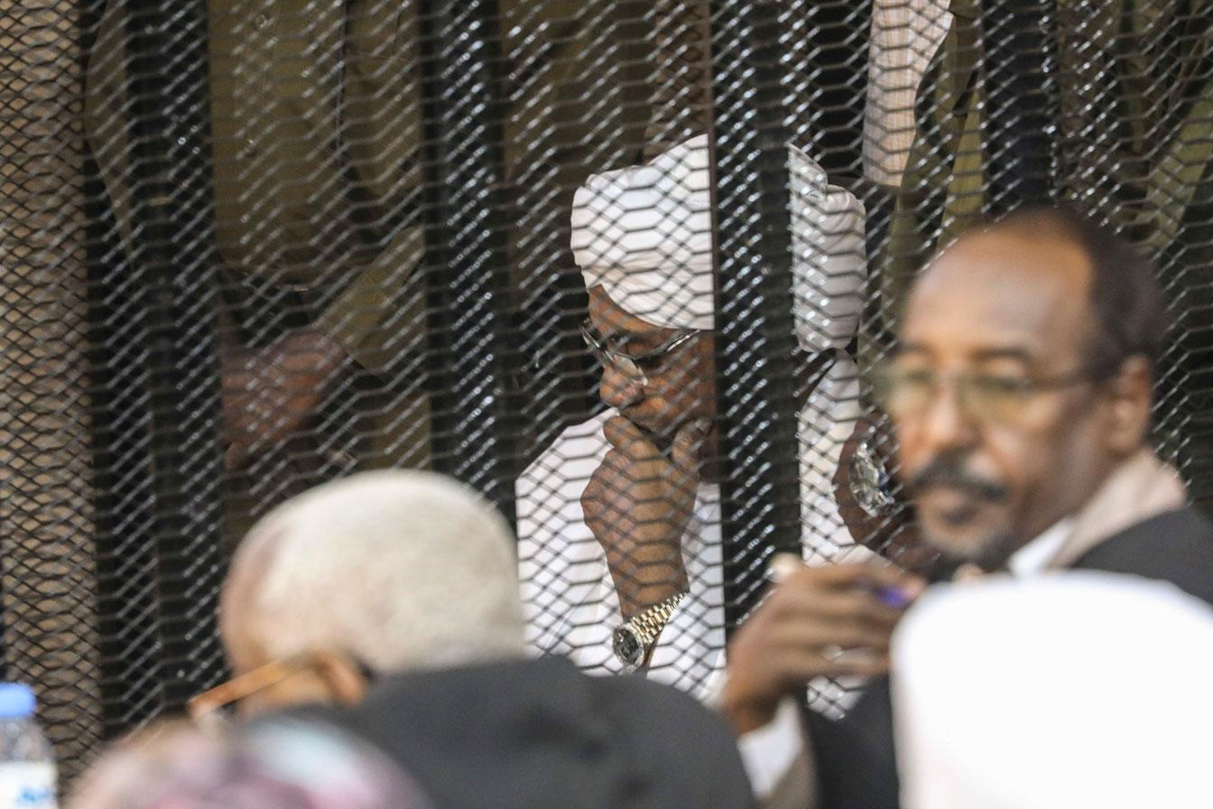 Sudan's autocratic former President Omar al-Bashir sits in a cage during his trial on corruption and money laundering charges in Khartoum