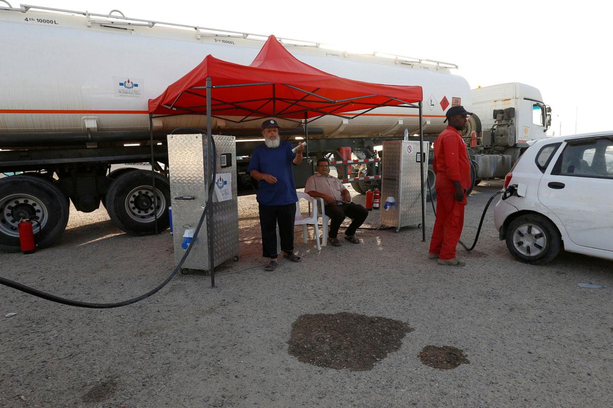 An employee of the state fuel distribution company, Brega, fills a car in Tripoli