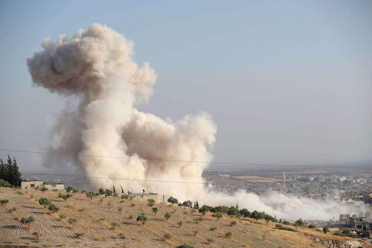 Smoke billowing above buildings during a reported air strike by pro-regime forces in Idlib province